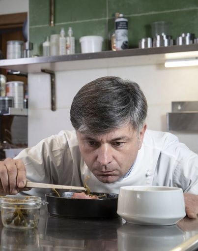 Cuoco che assaggia da una pentola con un cucchiaio di legno Cuoco che assaggia da una pentola con un cucchiaio di legno