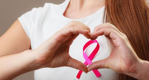 donna fa con la mani il simbolo della lotta al cancro al seno