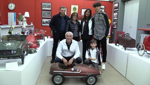 Persone accovacciate vicino a un modellino di auto in scala Persone accovacciate vicino a un modellino di auto in scala