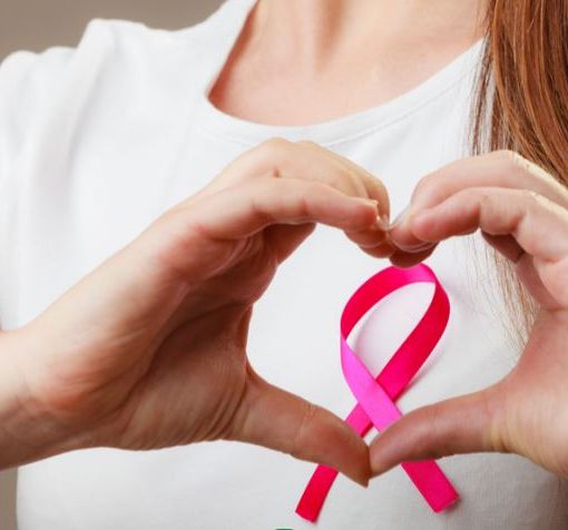 donna fa con la mani il simbolo della lotta al cancro al seno