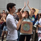 ragazzo davanti ad altri manifestanti con cartelli