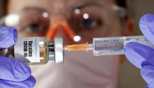 medico con una siringa in cui sta inserendo un vaccino
